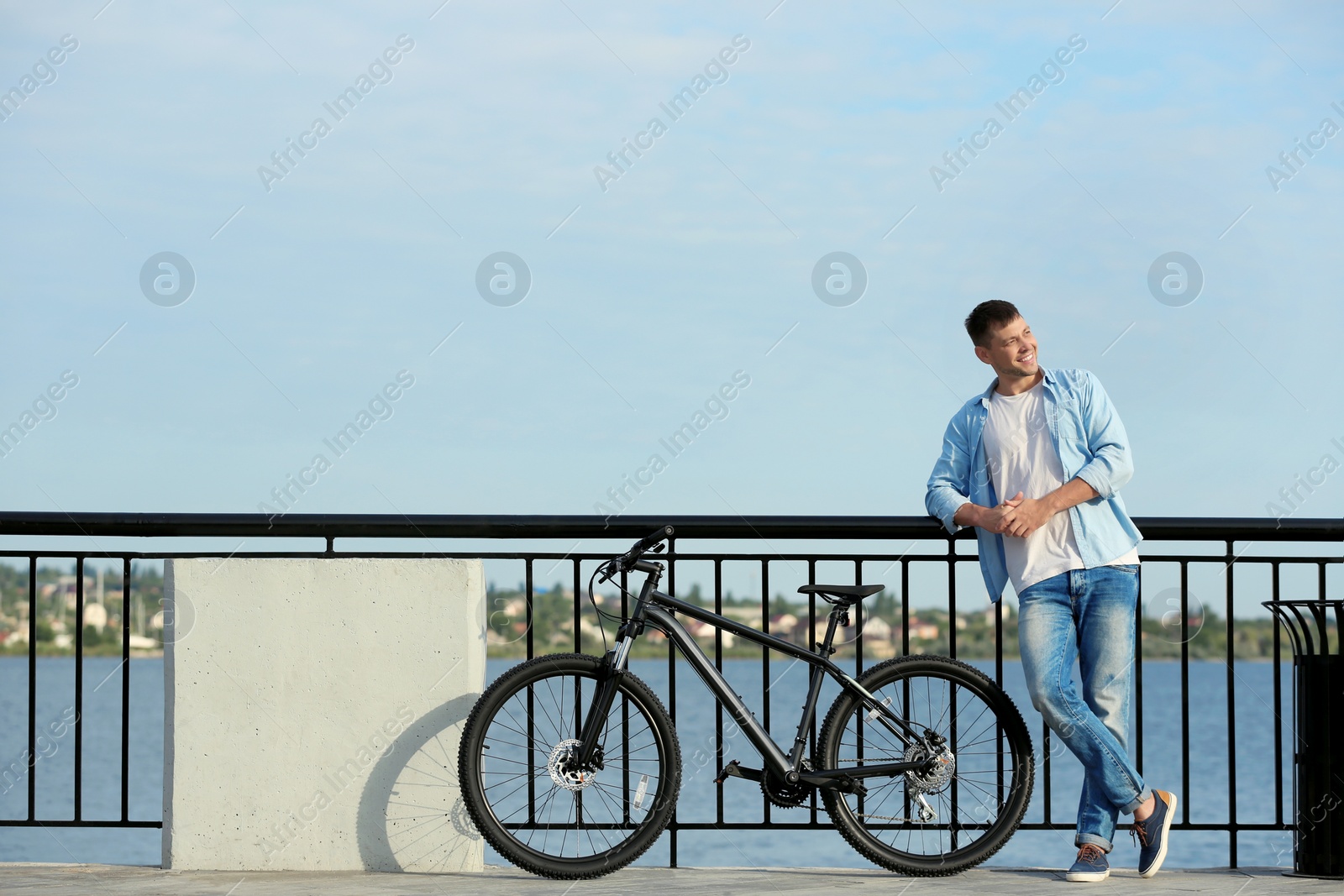 Photo of Handsome man with modern bicycle near river