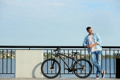 Handsome man with modern bicycle near river