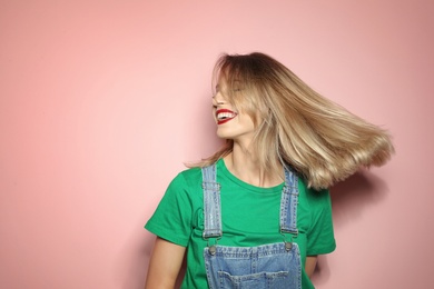 Photo of Beautiful young woman with healthy long blonde hair on color background