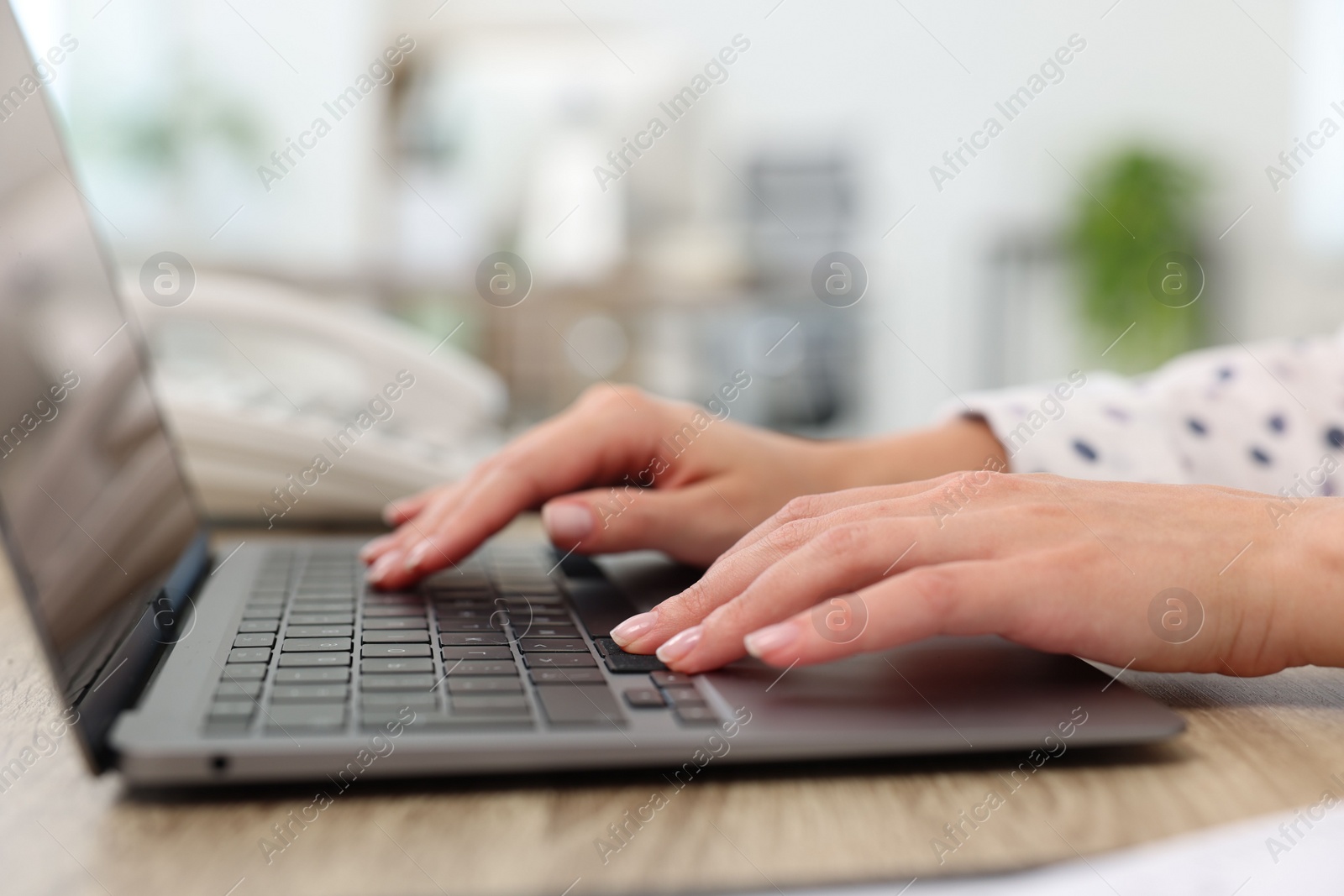 Photo of Secretary working with laptop at table in office, closeup