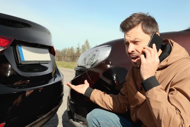 Photo of Man talking on phone near car with scratch outdoors Auto accident