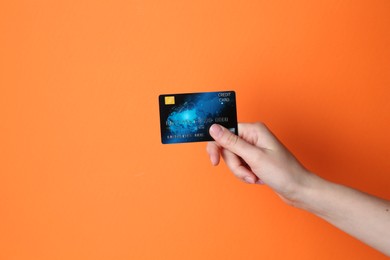 Photo of Woman holding credit card on orange background, closeup