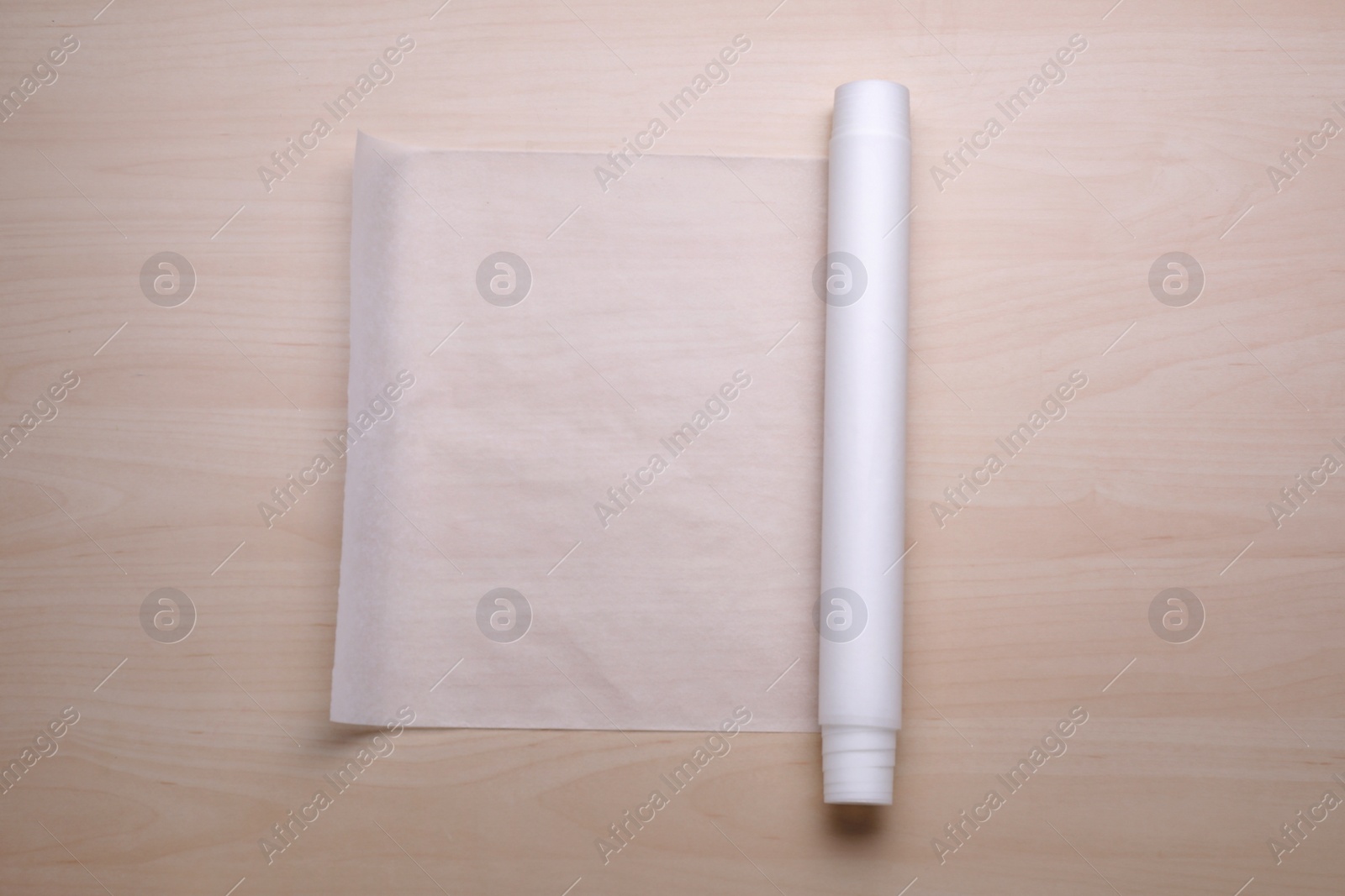 Photo of Roll of baking paper on wooden table, top view