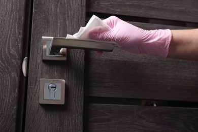 Photo of Woman wiping door handle with paper towel, closeup