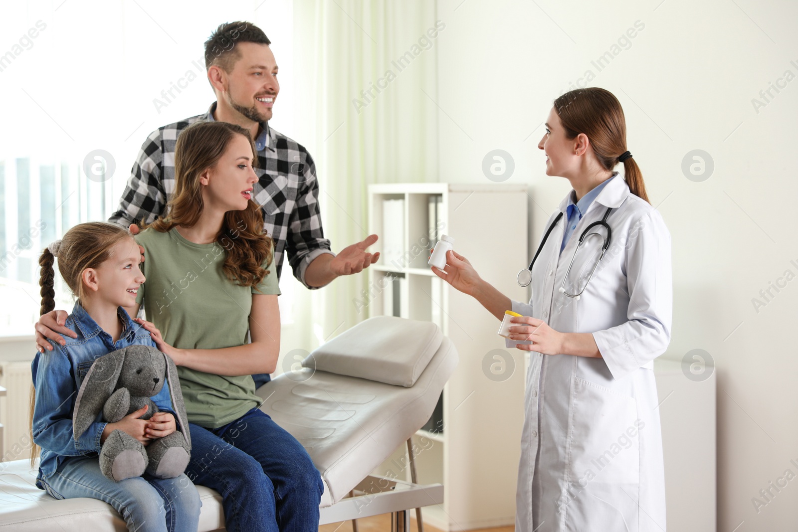 Photo of Parents and daughter visiting pediatrician. Doctor working with patient in hospital