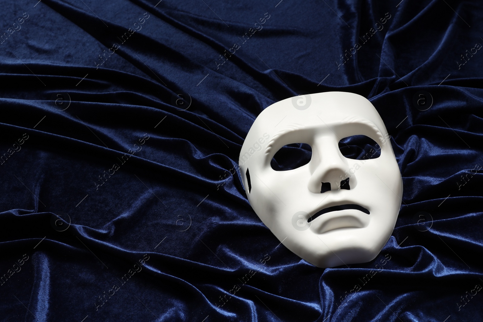 Photo of Theater arts. White mask on blue fabric, above view. Space for text