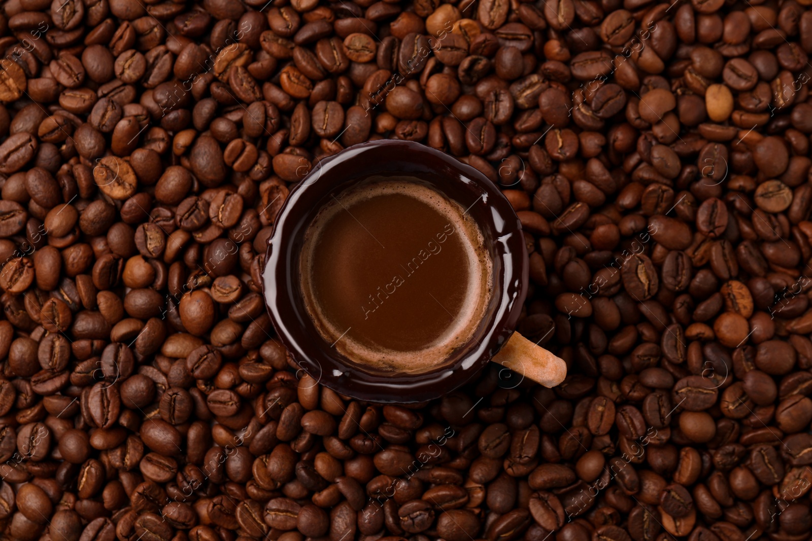 Photo of Delicious edible biscuit cup with espresso on roasted beans, top view