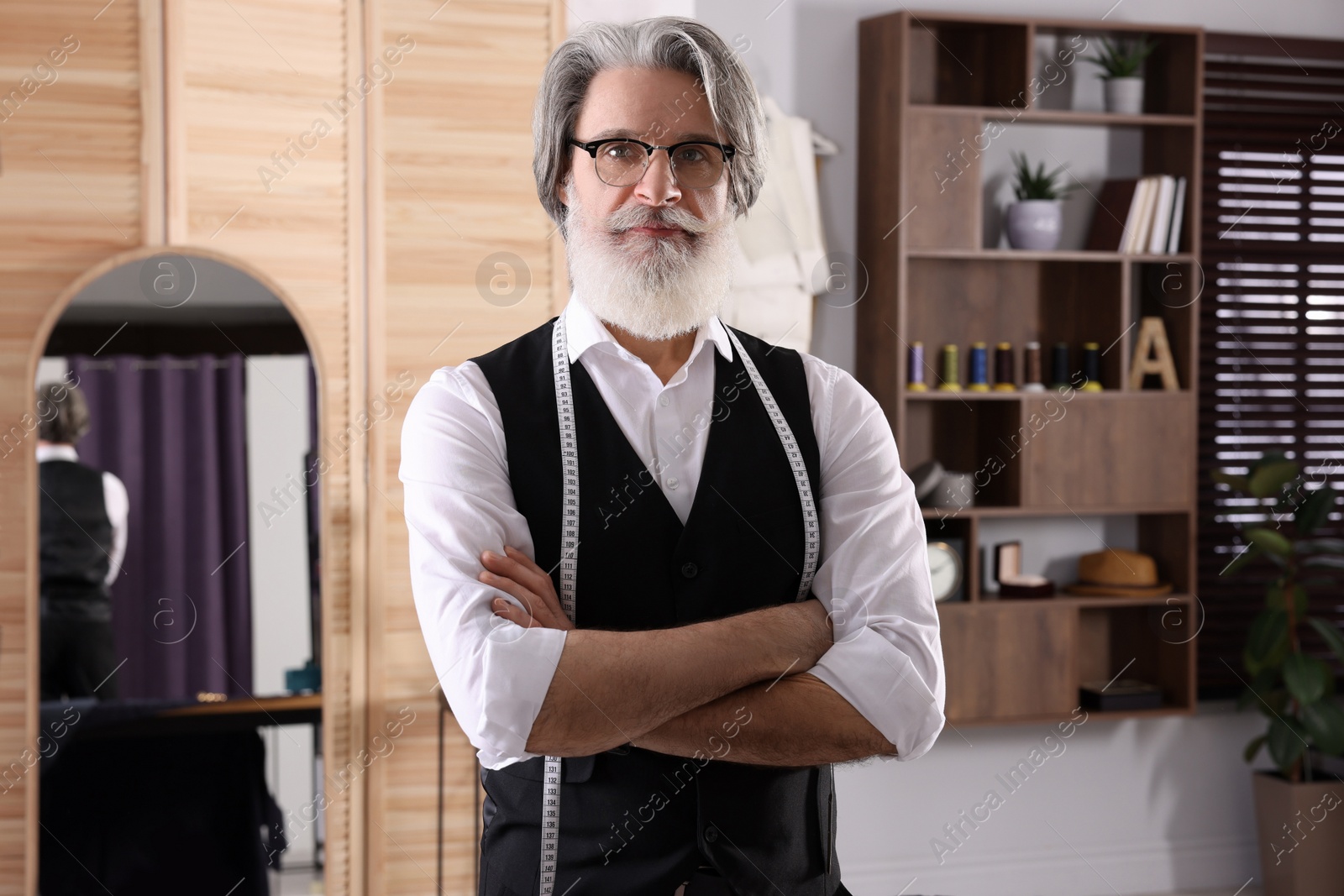 Photo of Professional tailor with measuring tape in workshop