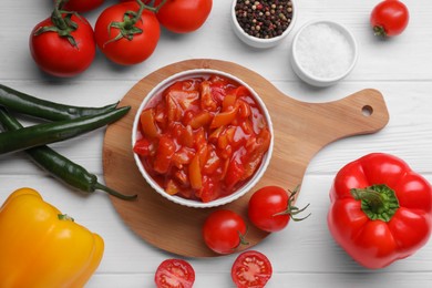 Delicious lecho in bowl and fresh ingredients on white wooden table, flat lay