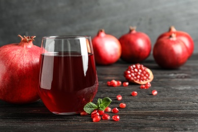 Photo of Glass of pomegranate juice and fresh fruits on table against grey background, space for text