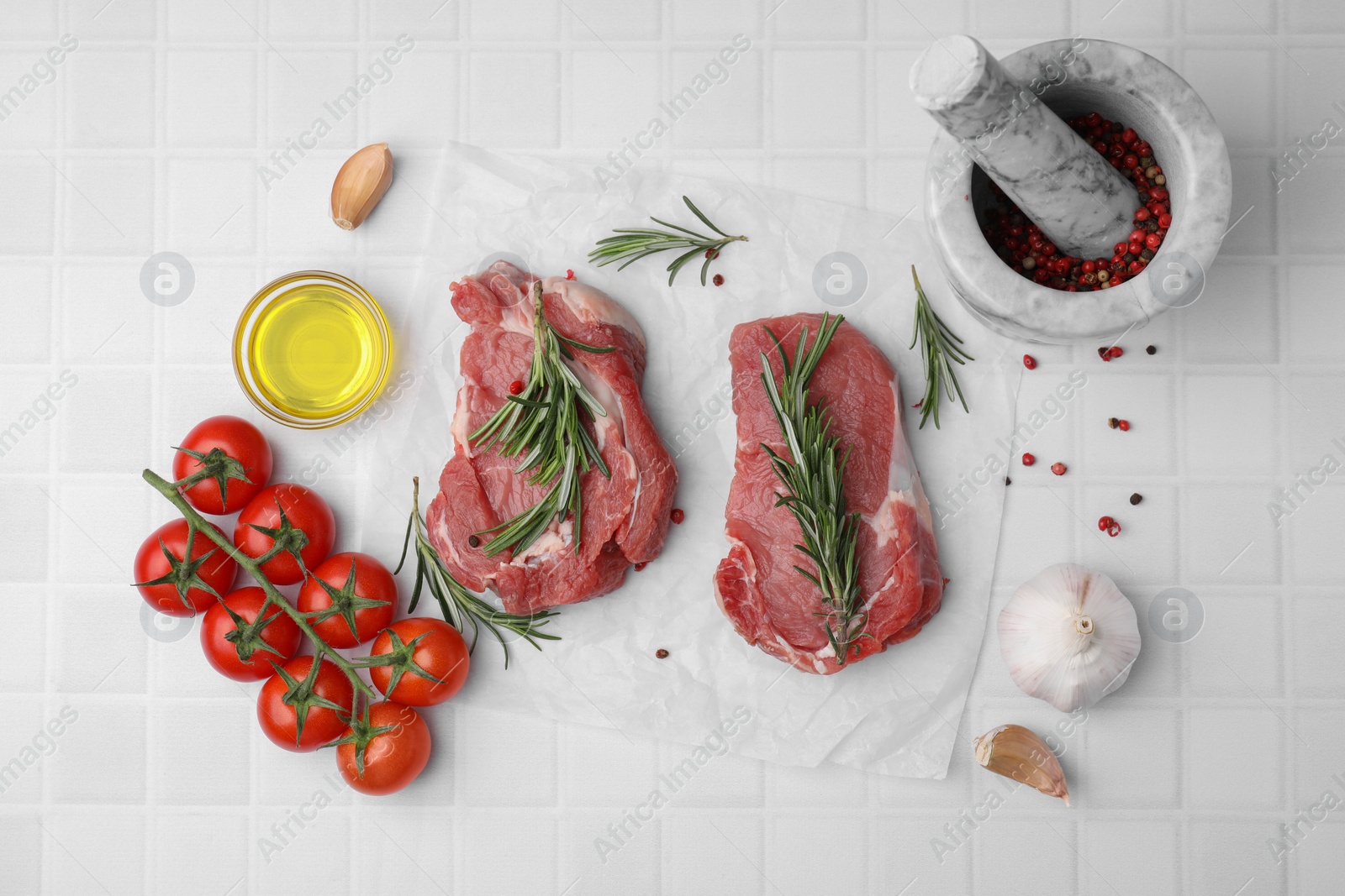 Photo of Fresh raw meat with rosemary, oil, tomatoes and spices on white tiled table, flat lay