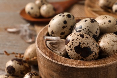 Photo of Wooden bowl with quail eggs on table, closeup