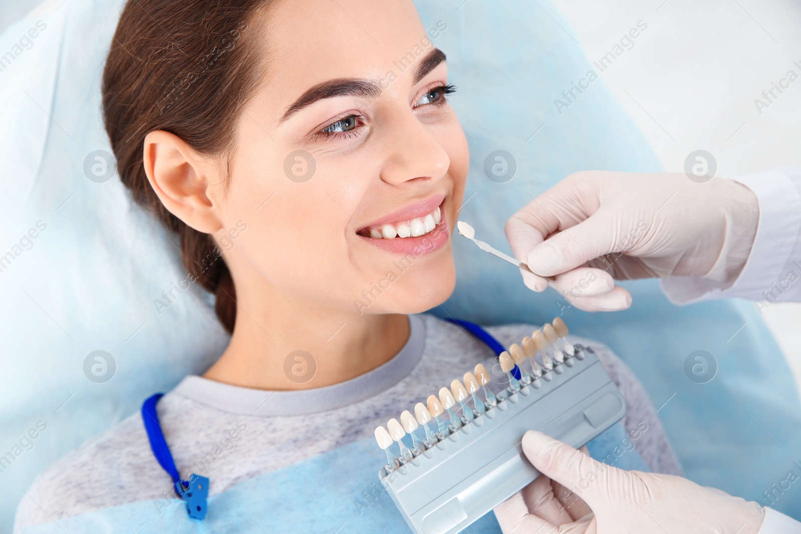 Photo of Dentist selecting patient's teeth color with palette in clinic