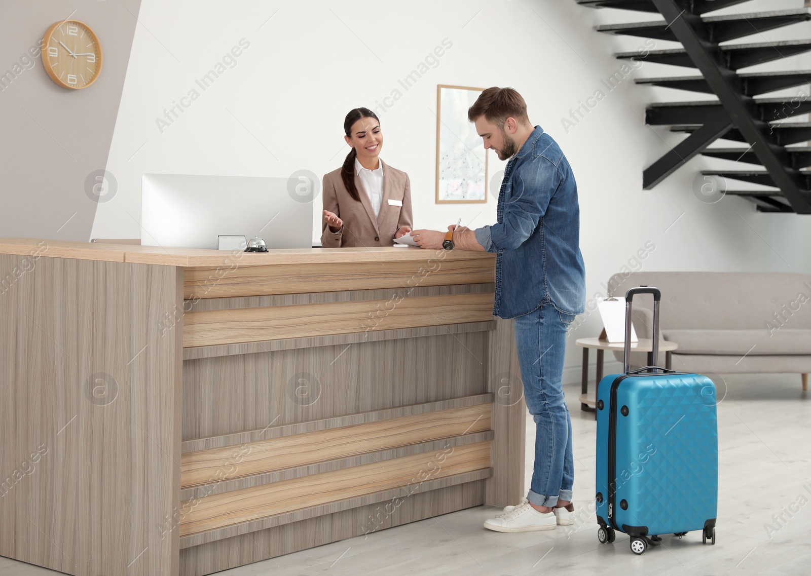 Photo of Professional receptionist working with client at desk in modern hotel