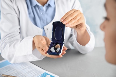 Doctor giving hearing aid to patient in hospital, closeup