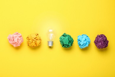 Creative flat lay composition with lightbulb and colorful paper balls on yellow background. Idea concept