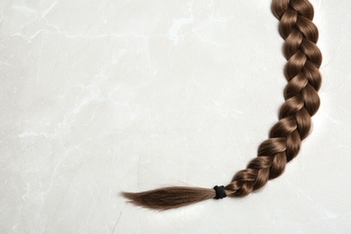 Photo of Braided hair on grey background, top view with space for text
