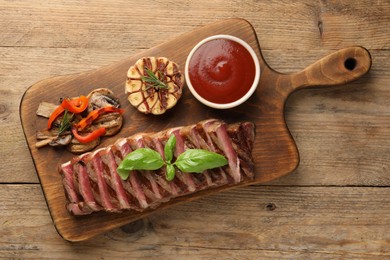Delicious grilled beef steak with spices and tomato sauce on wooden table, top view