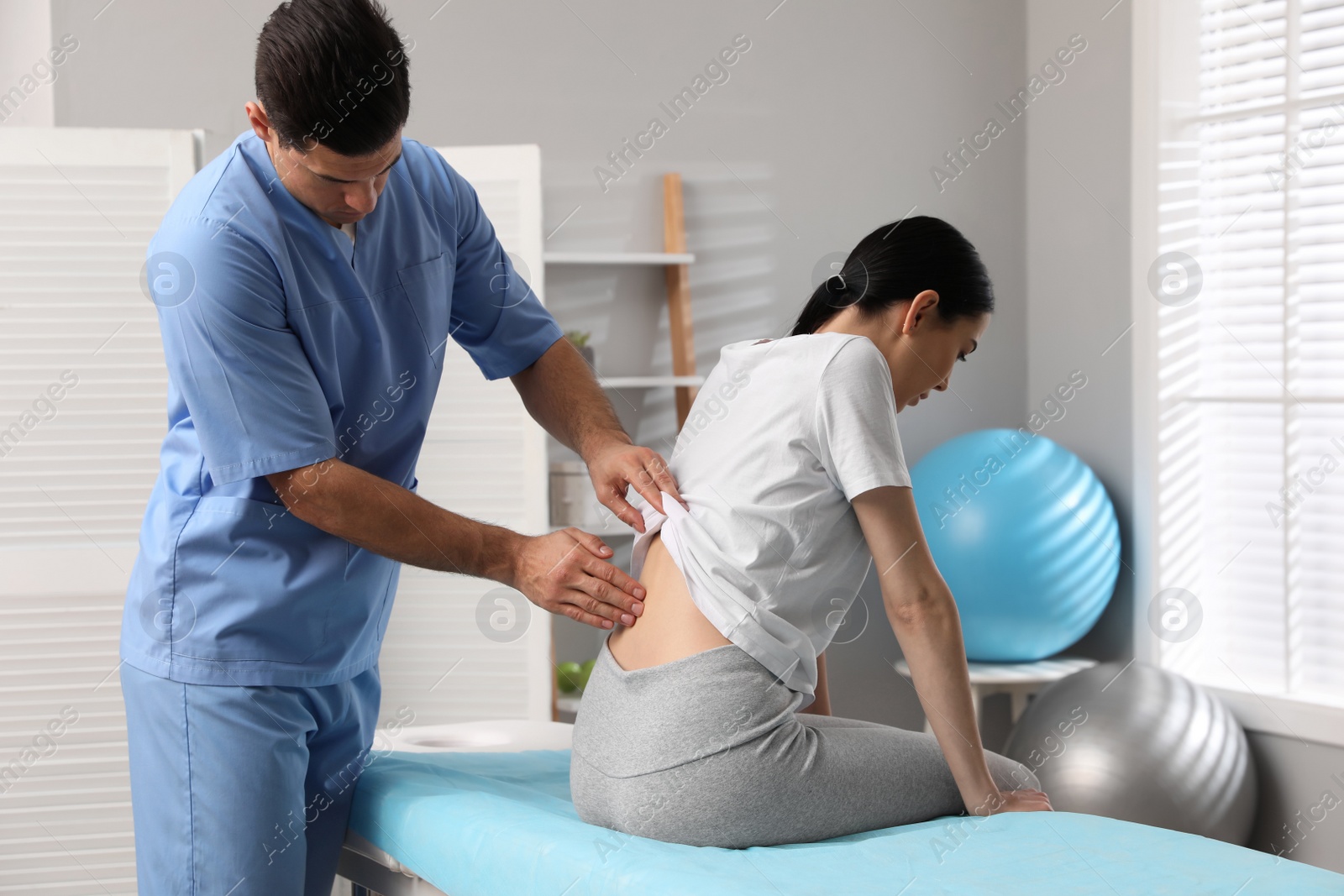 Photo of Orthopedist examining woman's back in clinic. Scoliosis treatment