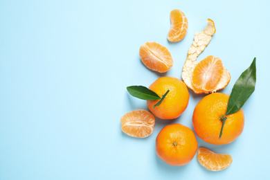 Photo of Flat lay composition with fresh ripe tangerines and leaves on light blue background, space for text. Citrus fruit