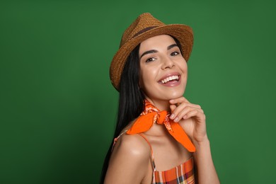 Fashionable young woman in stylish outfit with bandana on green background