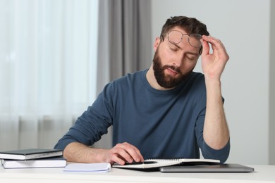 Overwhelmed man with glasses at table indoors