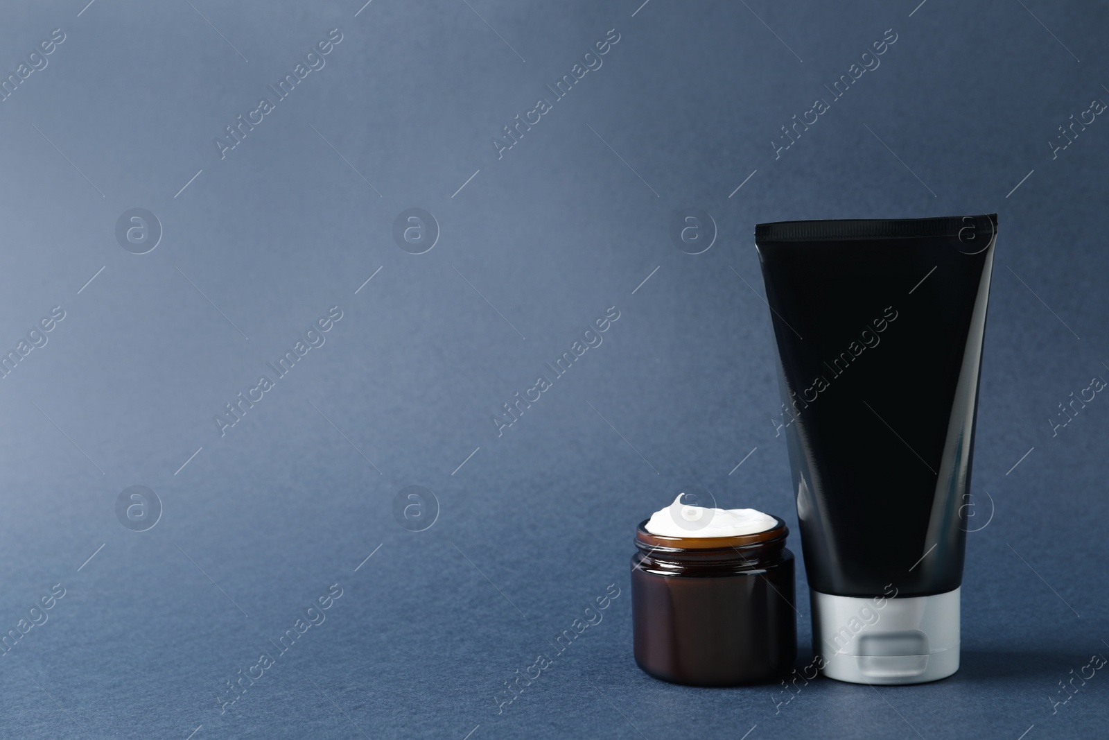 Photo of Tube and jar of men's facial cream on grey background. Space for text