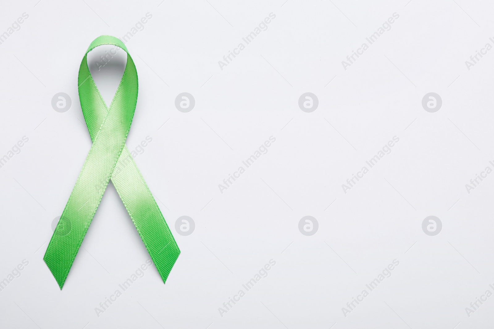 Photo of World Mental Health Day. Green ribbon on white background, top view with space for text