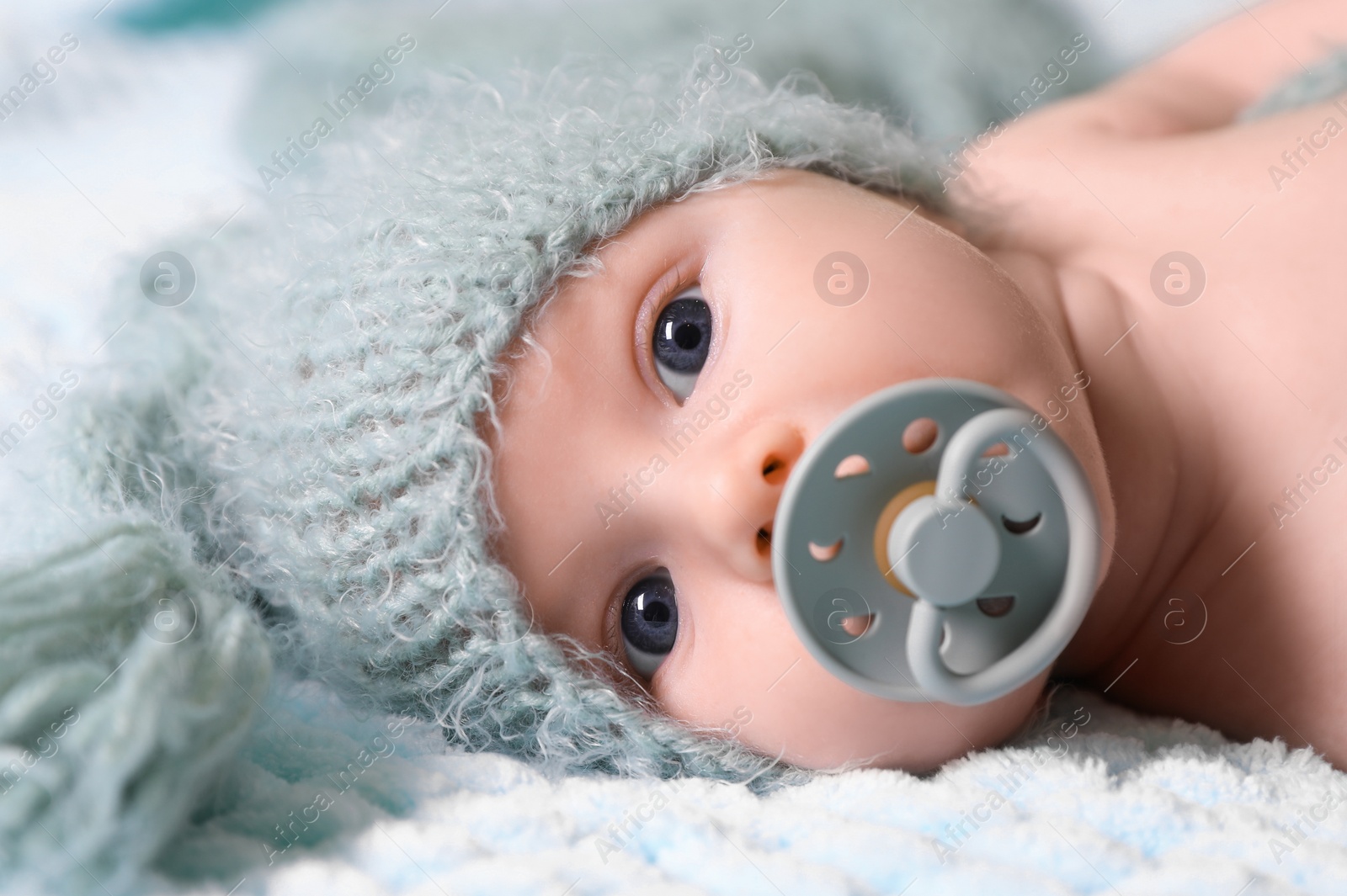 Photo of Cute newborn baby with pacifier on soft blanket, closeup