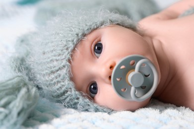 Cute newborn baby with pacifier on soft blanket, closeup