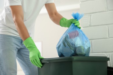 Photo of Man throwing garbage bag into bin at home, closeup