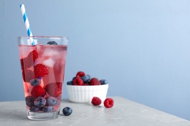 Photo of Delicious berry lemonade made with soda water on grey marble table. Space for text