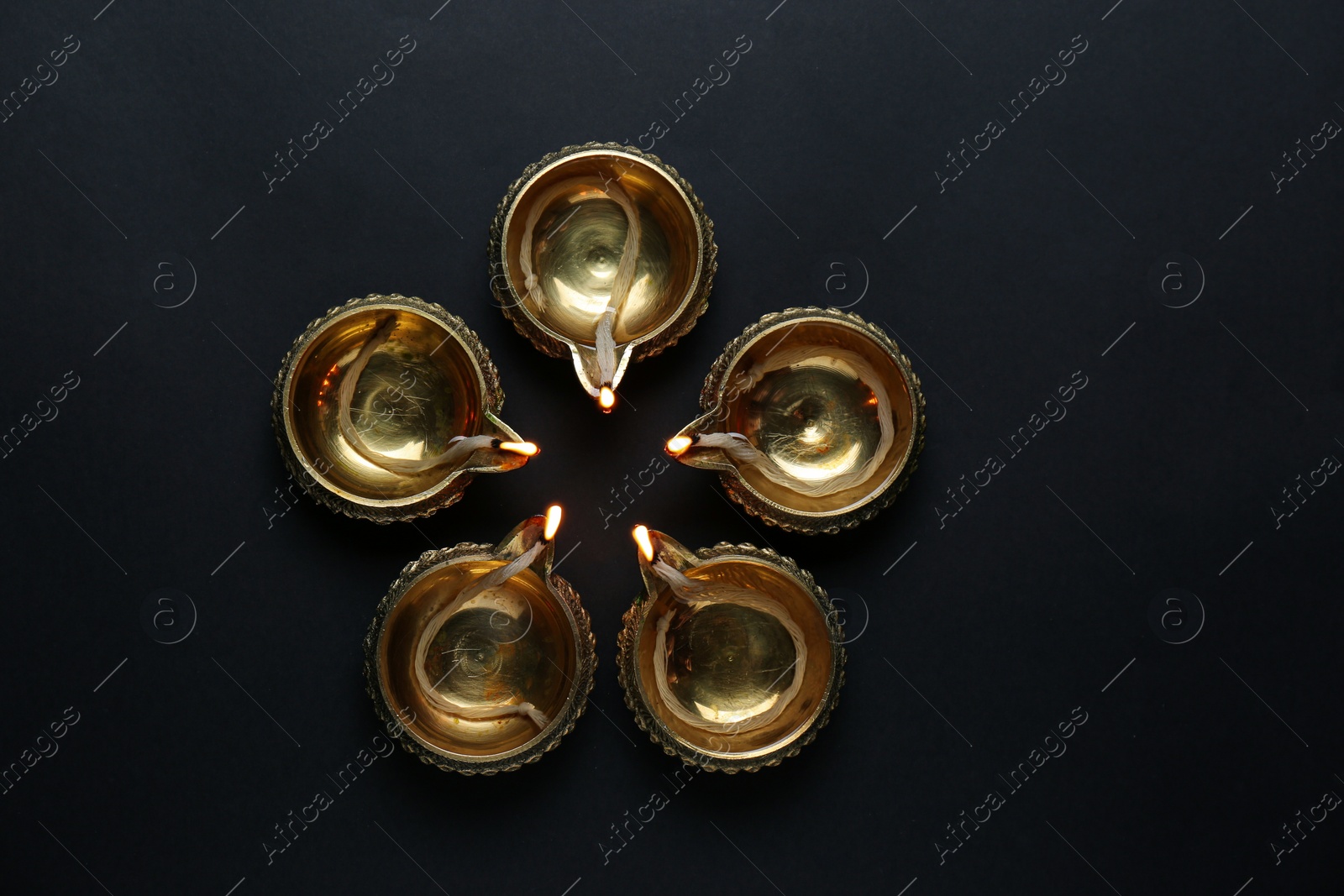 Photo of Lit diyas on dark background, flat lay. Diwali lamps