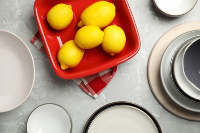 Set of ceramic dishware and fresh lemons on grey marble table, flat lay