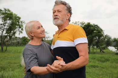 Happy mature couple dancing in green park