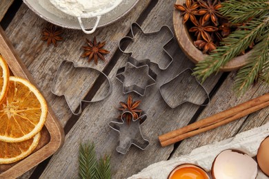 Photo of Flat lay composition with cookie cutters and ingredients on wooden table. Christmas biscuits