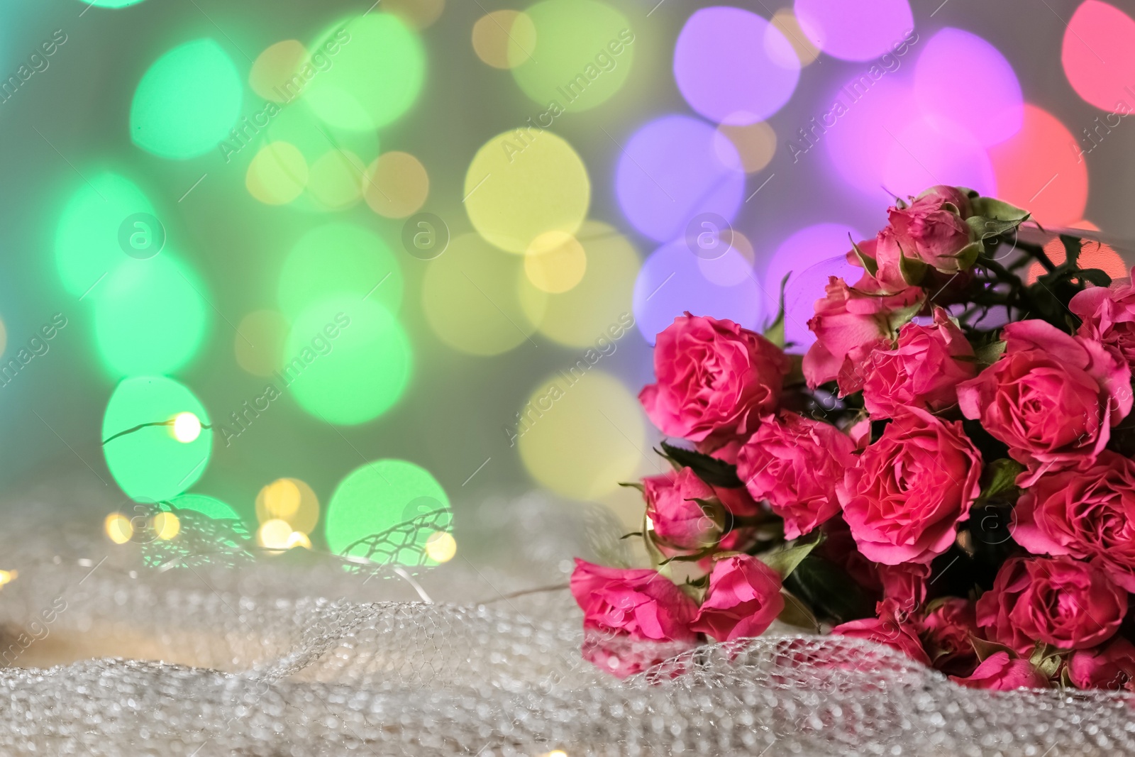 Photo of Fresh bouquet on mesh fabric against blurred lights, space for text. Bokeh effect