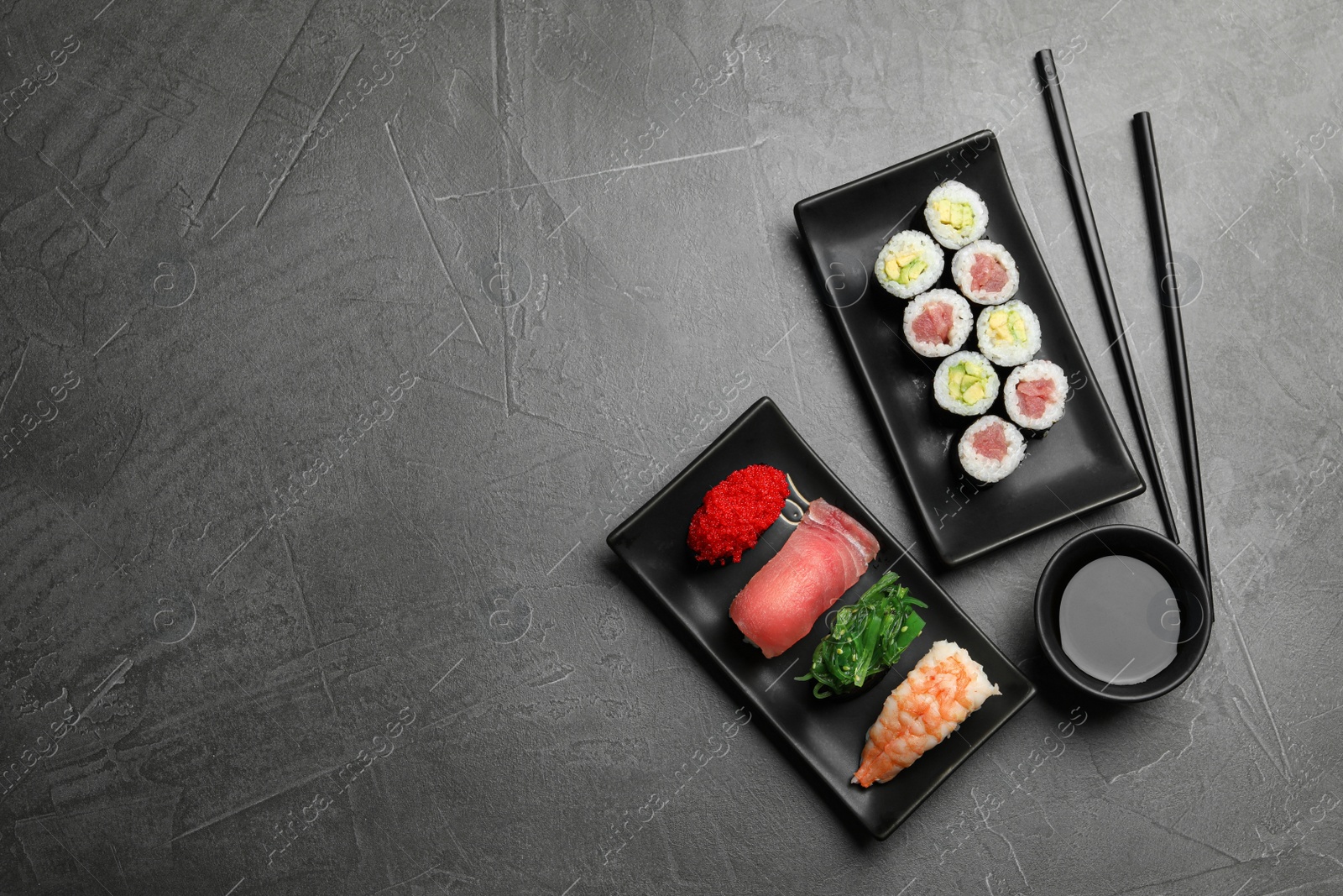 Photo of Set of delicious sushi and rolls on grey table, flat lay. Space for text