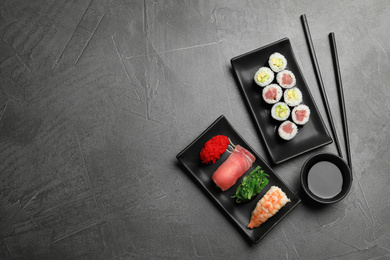 Photo of Set of delicious sushi and rolls on grey table, flat lay. Space for text