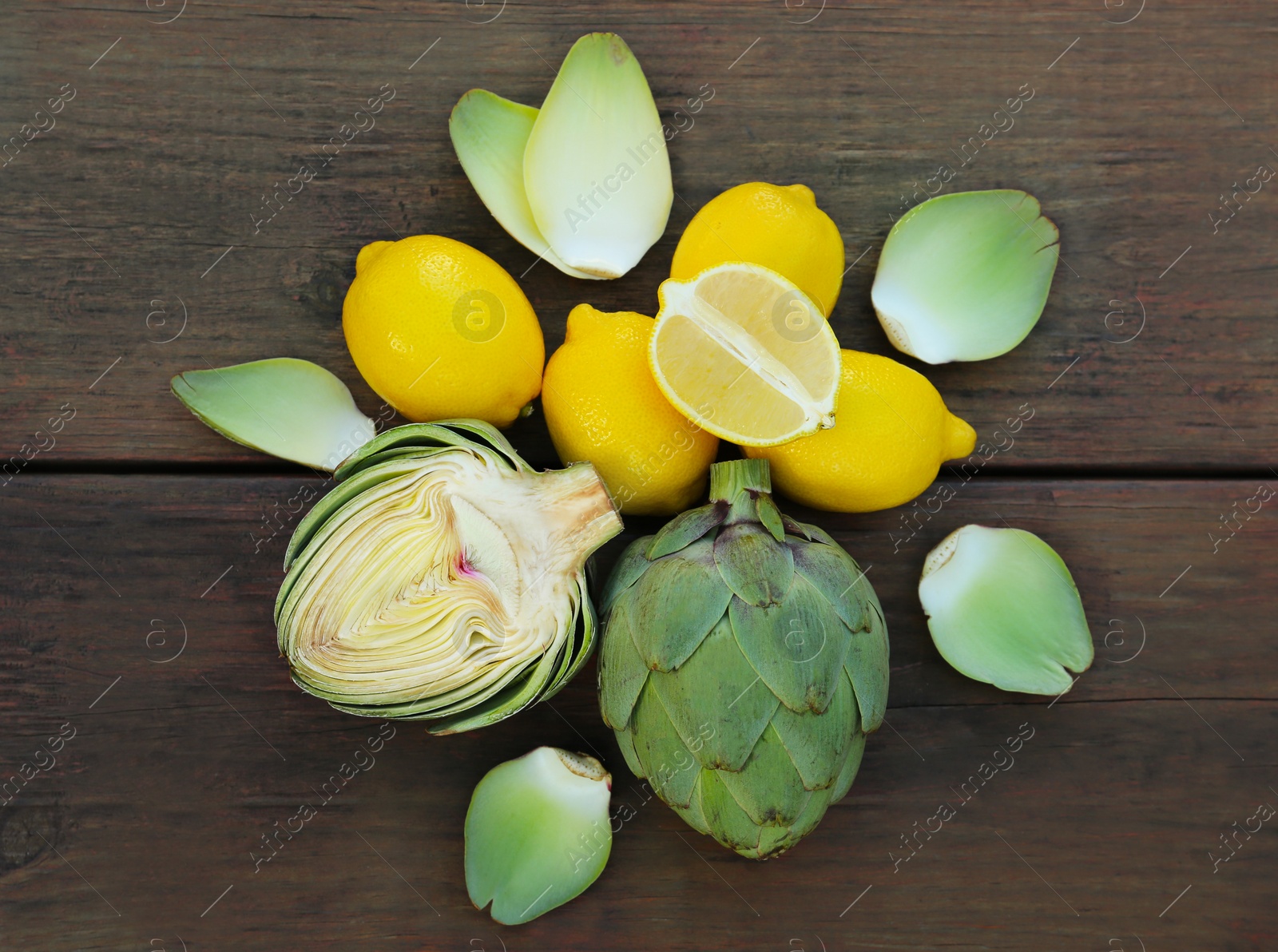 Photo of Artichokes and lemons on wooden table, flat lay