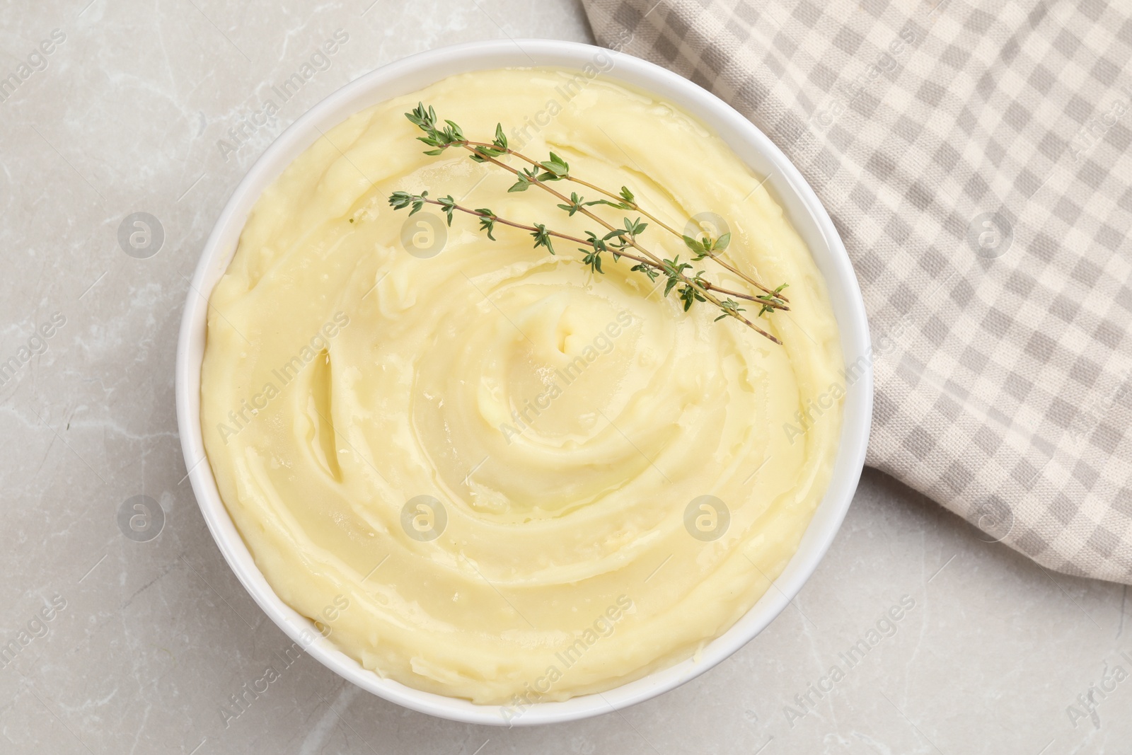 Photo of Bowl of tasty mashed potato with rosemary on grey marble table, flat lay