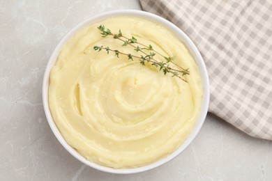 Bowl of tasty mashed potato with rosemary on grey marble table, flat lay