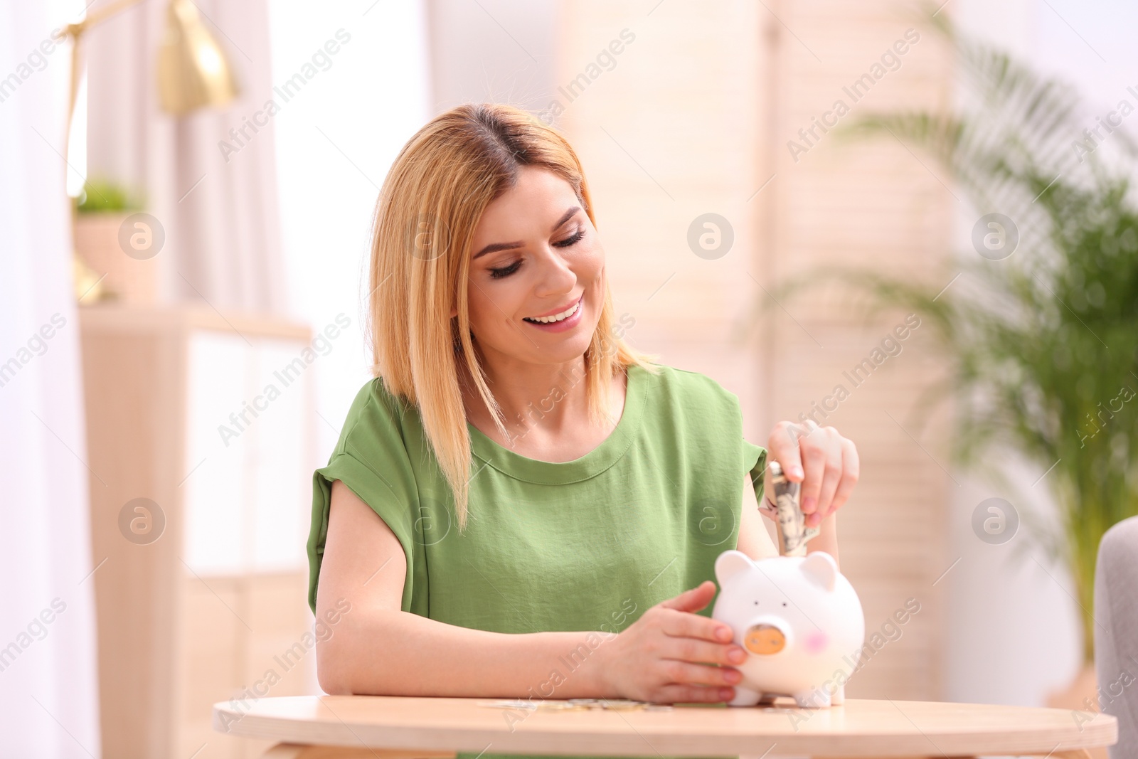 Photo of Woman with piggy bank and money at home