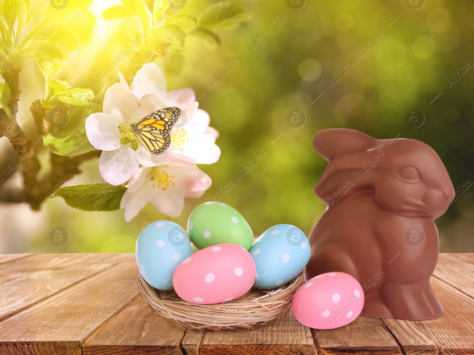 Image of Sweet chocolate bunny and colorful eggs on wooden table outdoors. Easter celebration