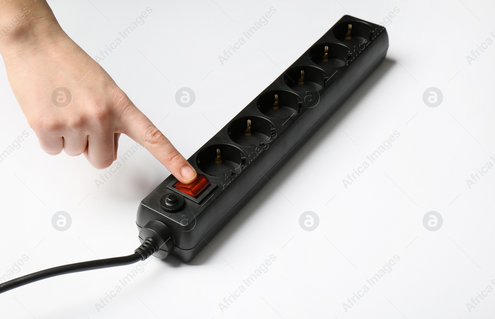 Photo of Woman pressing power button of extension cord on white background, closeup. Electrician's equipment