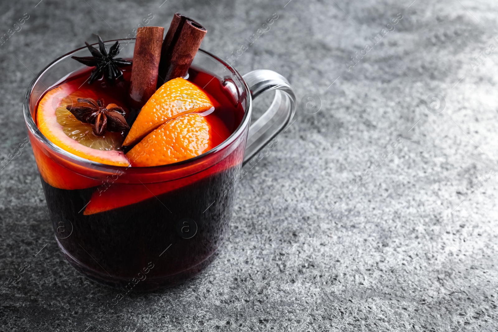 Photo of Aromatic mulled wine on grey table. Space for text