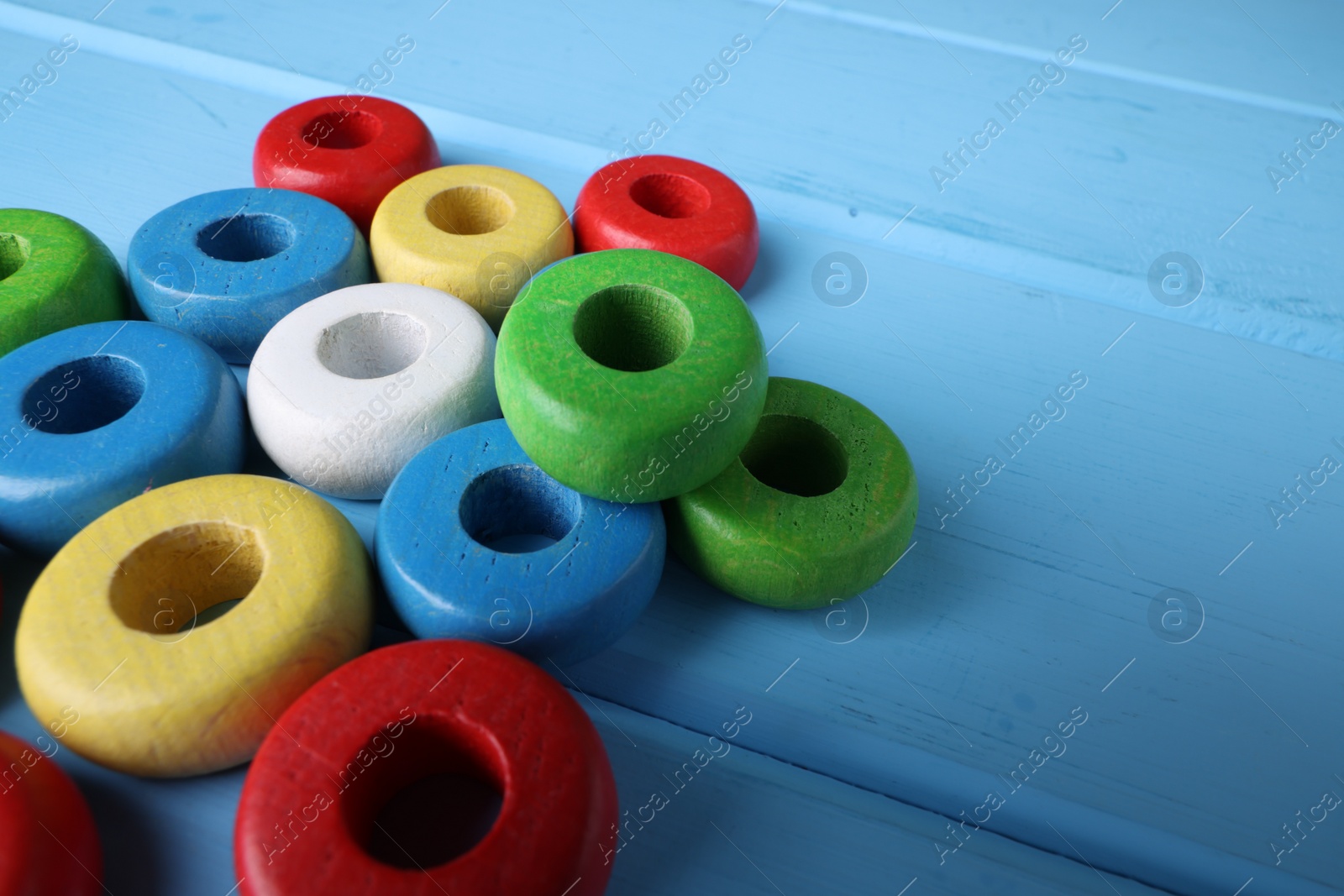 Photo of Colorful pieces of educational toy on light blue wooden table, closeup and space for text. Motor skills development