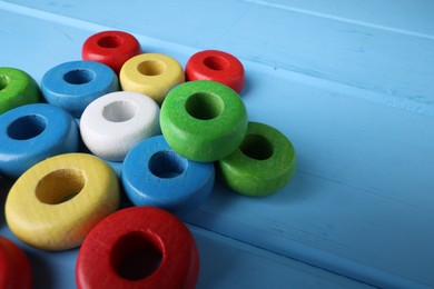 Colorful pieces of educational toy on light blue wooden table, closeup and space for text. Motor skills development