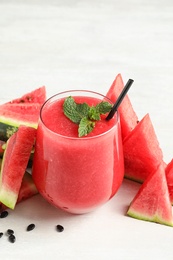 Photo of Summer watermelon drink in glass and sliced fresh fruit on table