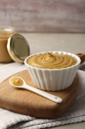 Photo of Bowl and spoon with tasty mustard sauce on light table
